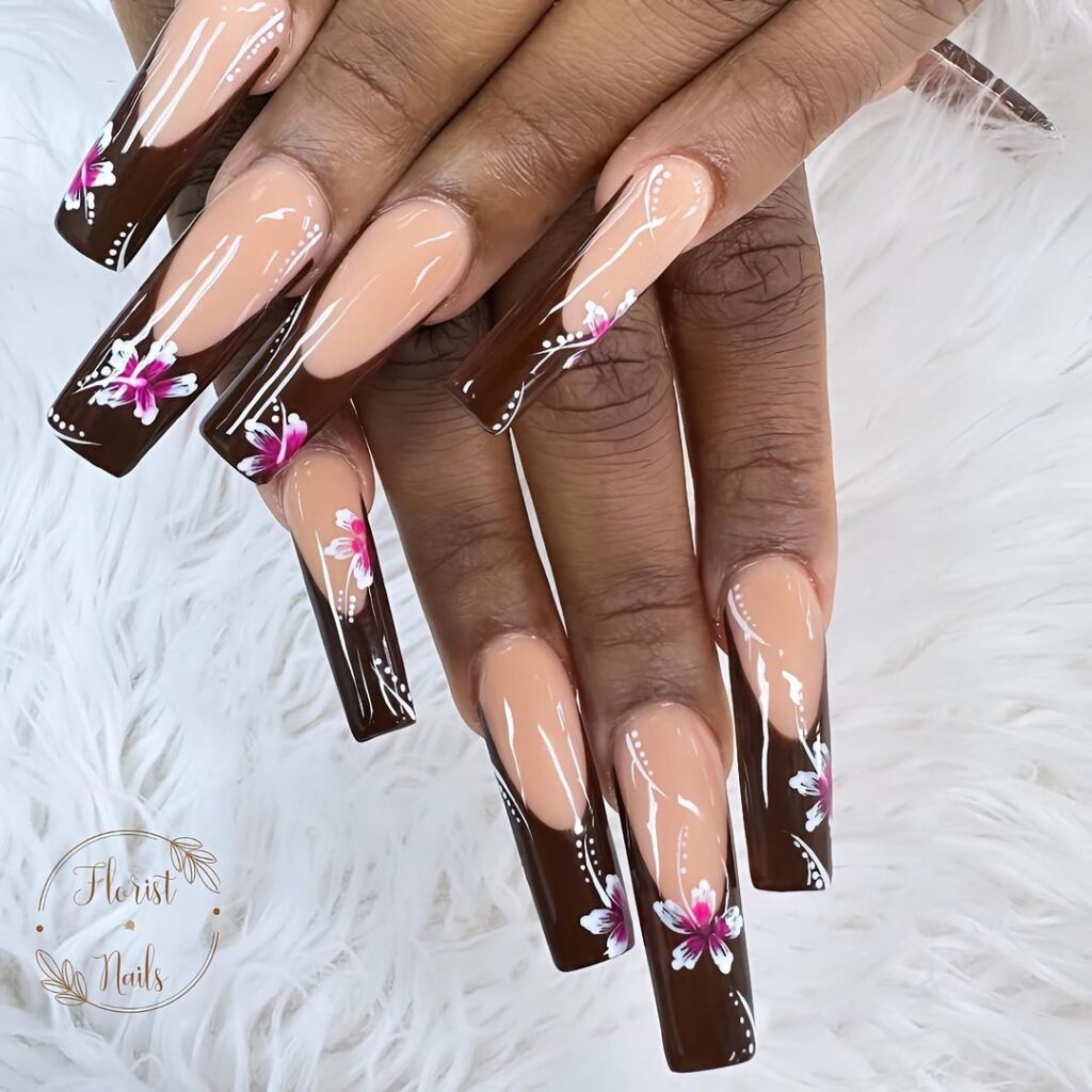 hands with nails that have floral designs in brown, purple and white