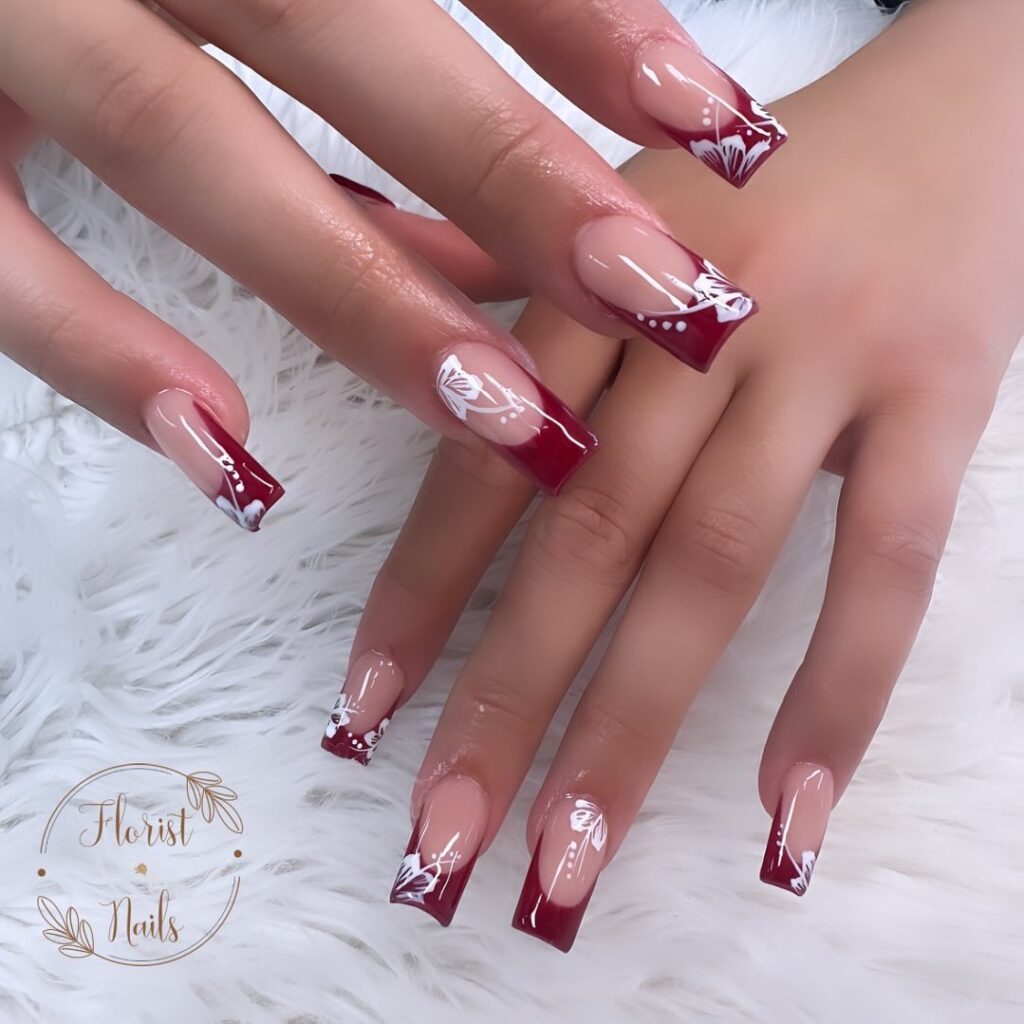 hands with nails that have floral designs in burgundy and white