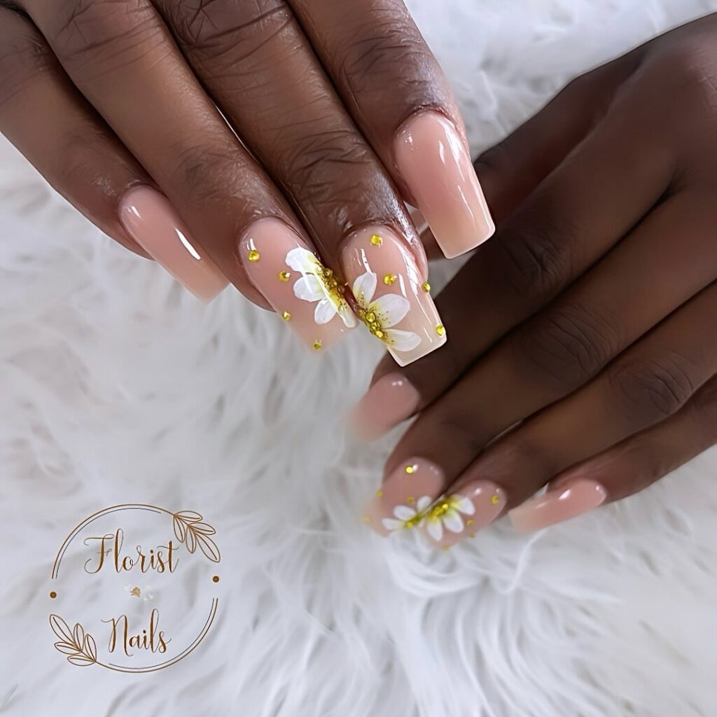 hands with nails that have floral designs in gold and white