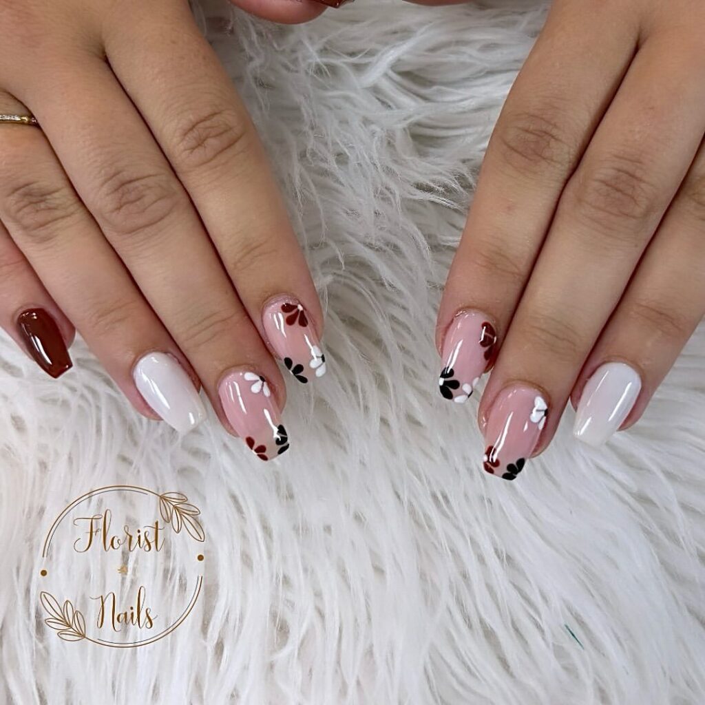 hands with nails polished in burgundy, white and floral designs