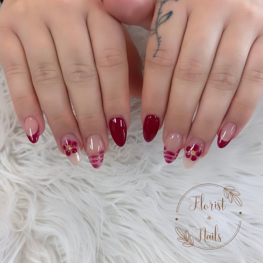 hands with nails designed in burgundy flowers