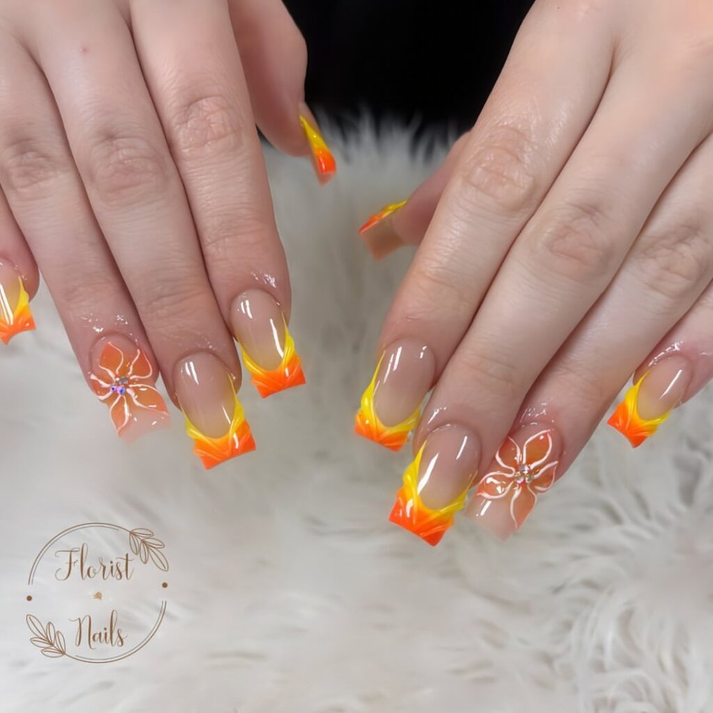 hands with nails that have floral designs and French tips in orange and yellow