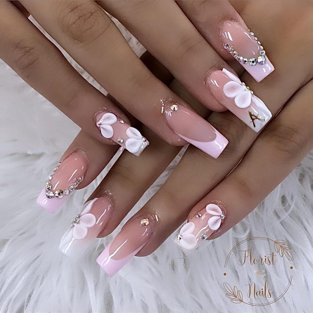 hands with nails that have floral designs in white and pink